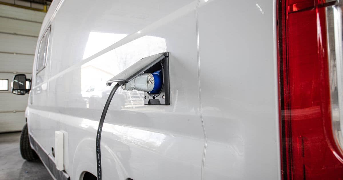 Landstrømskabel tilsluttet indtaget på siden af en autocamper